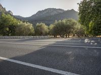 a motorcycle is parked in the road by trees and hills in the sun setting,