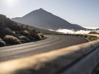 the man in the black suit is running down the road with his bicycle near the mountain