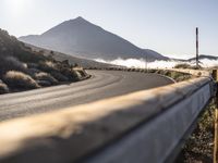 the man in the black suit is running down the road with his bicycle near the mountain