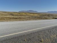 a motorcycle traveling on an empty rural highway with mountain in the background and no people in the area