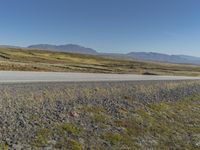 a motorcycle traveling on an empty rural highway with mountain in the background and no people in the area