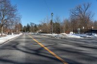 empty street and a stoplight at the side of it in winter time with lots of snow on the road