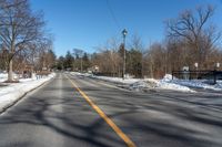 empty street and a stoplight at the side of it in winter time with lots of snow on the road