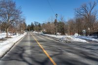 empty street and a stoplight at the side of it in winter time with lots of snow on the road