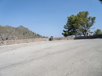 an empty street that has a bench next to it with a mountain in the background