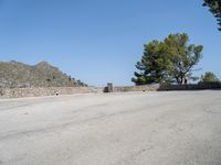 an empty street that has a bench next to it with a mountain in the background