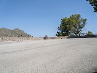 an empty street that has a bench next to it with a mountain in the background