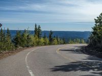 the mountains are visible in the distance from this wide, empty road, overlooking a wide landscape and forest