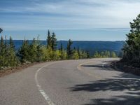 the mountains are visible in the distance from this wide, empty road, overlooking a wide landscape and forest