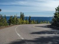 the mountains are visible in the distance from this wide, empty road, overlooking a wide landscape and forest