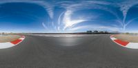 the wide angle photo of a panoramic picture taken of an asphalt track with a house in the background