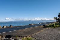 the asphalted roadway winds along a rocky coastline and stretches out across the water from an ocean