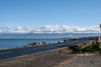 the asphalted roadway winds along a rocky coastline and stretches out across the water from an ocean