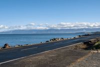 the asphalted roadway winds along a rocky coastline and stretches out across the water from an ocean