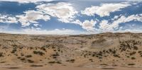 a desert with lots of sand and trees on top of it under a cloudy blue sky