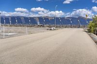 the gravel road leads to a parking lot, lined by solar panels on the horizon