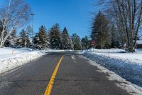 road in winter with yellow painted lines on street and snowbanks on the roadside