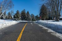 road in winter with yellow painted lines on street and snowbanks on the roadside