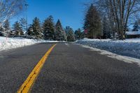 road in winter with yellow painted lines on street and snowbanks on the roadside