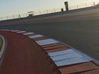 an orange and white racing track with red and white strips on the front corner of the track