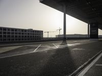 an empty street with the sun shining down through the building, showing a crane at the top