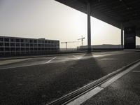 an empty street with the sun shining down through the building, showing a crane at the top