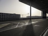 an empty street with the sun shining down through the building, showing a crane at the top