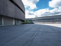 a concrete building has a red fire hydrant in a courtyard area with clouds overhead