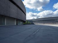 a concrete building has a red fire hydrant in a courtyard area with clouds overhead