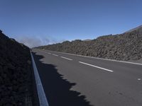 the desert road is lined with lava on either side of the highway, and many lavas are coming out from a large hill