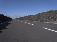 the desert road is lined with lava on either side of the highway, and many lavas are coming out from a large hill