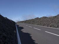 the desert road is lined with lava on either side of the highway, and many lavas are coming out from a large hill