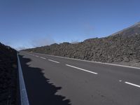 the desert road is lined with lava on either side of the highway, and many lavas are coming out from a large hill