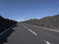 the desert road is lined with lava on either side of the highway, and many lavas are coming out from a large hill