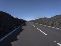 the desert road is lined with lava on either side of the highway, and many lavas are coming out from a large hill