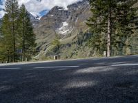 the road is empty on this mountain top side, with pine trees and rocks in it