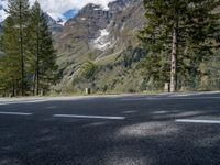 the road is empty on this mountain top side, with pine trees and rocks in it