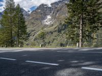 the road is empty on this mountain top side, with pine trees and rocks in it