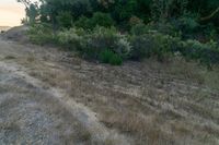 there is a sunset in the horizon on a field with grassy land below the mountains