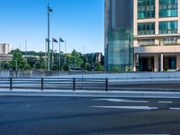 an empty road with a street sign at the curb in front of an office building