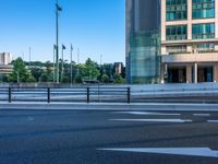 an empty road with a street sign at the curb in front of an office building