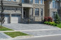 driveway is paved with brick blocks, and two doors are shown on either side of the driveway