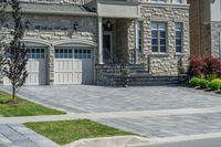 driveway is paved with brick blocks, and two doors are shown on either side of the driveway