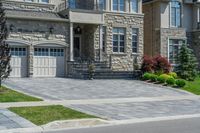 driveway is paved with brick blocks, and two doors are shown on either side of the driveway