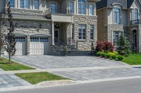 driveway is paved with brick blocks, and two doors are shown on either side of the driveway