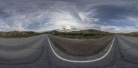 a wide angle photo of a view on an empty street and mountains in the background