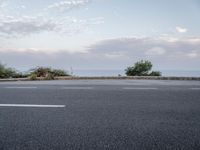 an image of a asphalt road with no parking space on it's side, and a view across the road from the sea