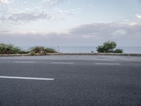 an image of a asphalt road with no parking space on it's side, and a view across the road from the sea