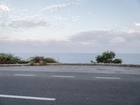 an image of a asphalt road with no parking space on it's side, and a view across the road from the sea