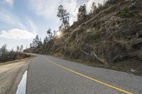 the view of a curve on a long road through some trees and rocks near the edge